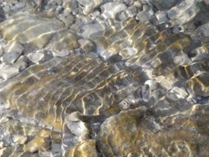 Tirage photo d’art – douces ondulations à la surface d’une rivière, galets visibles sous l’eau