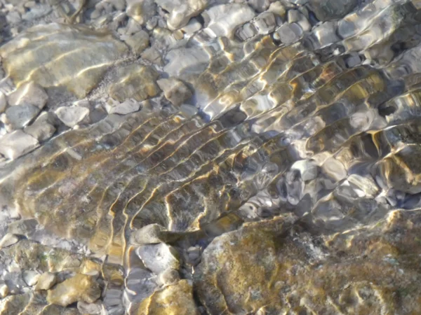 Tirage photo d’art – douces ondulations à la surface d’une rivière, galets visibles sous l’eau